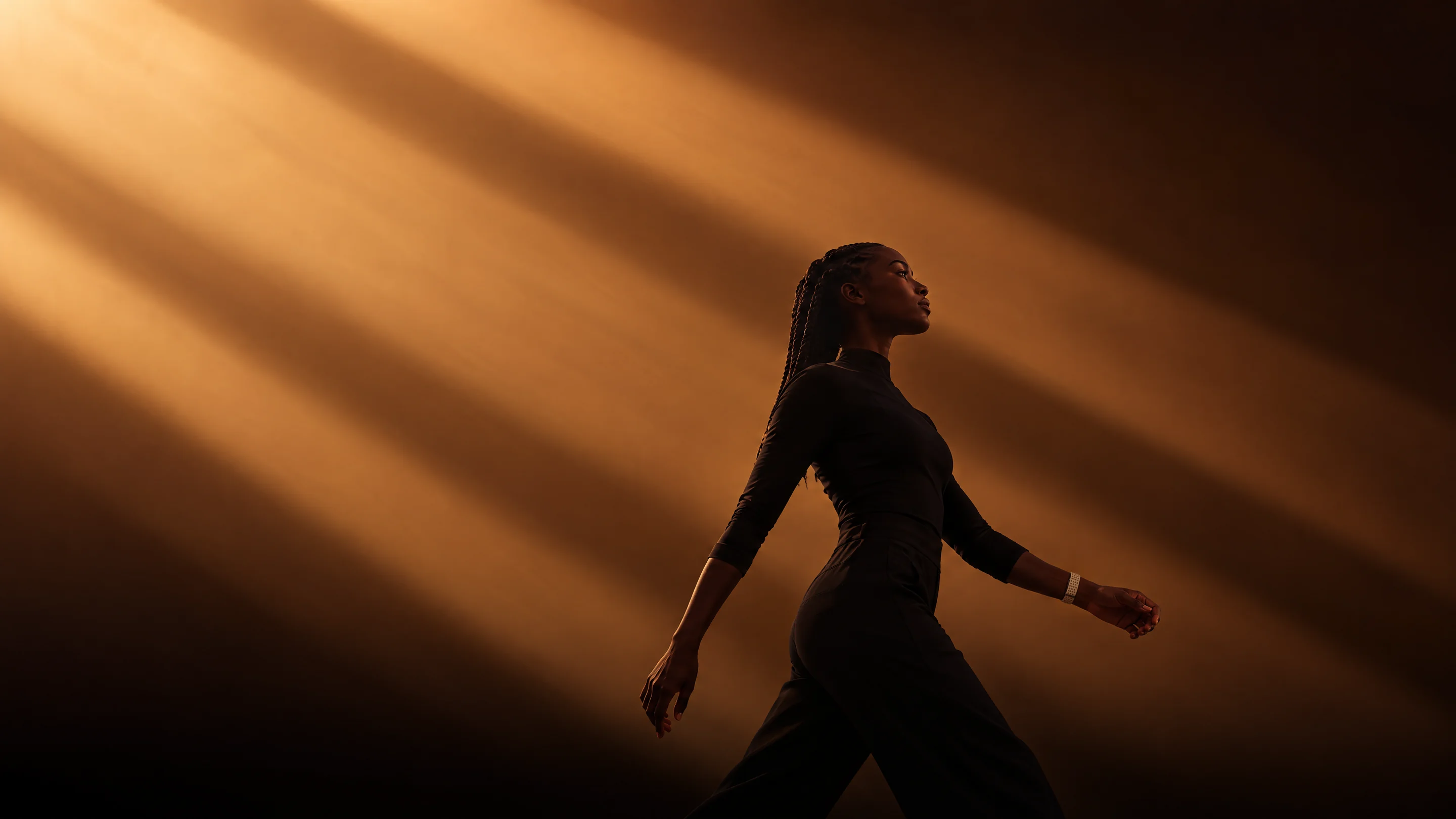 A woman striding through beams of amber light, wearing the PhenomeTech Band in Dune