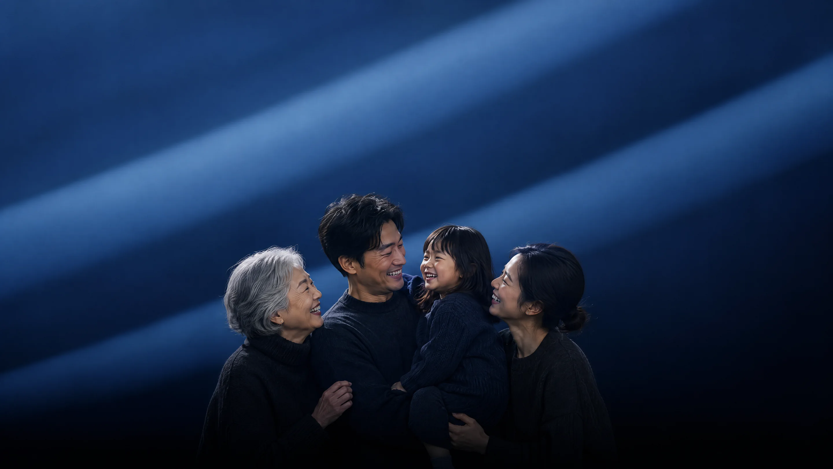 A grandmother, her son and his wife laughing with their little daughter in beams of blue light