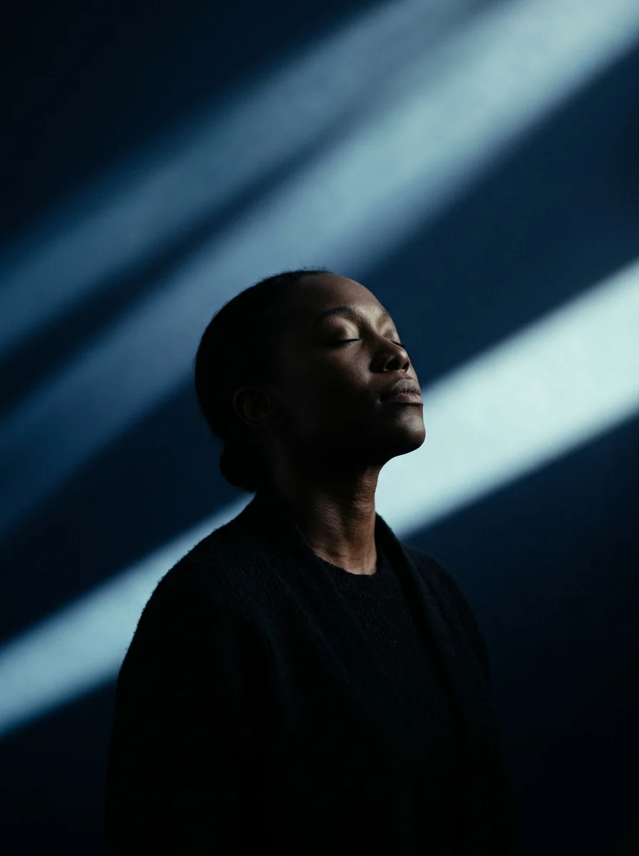 A woman with her eyes closed, turned up into beams of navy and cyan light