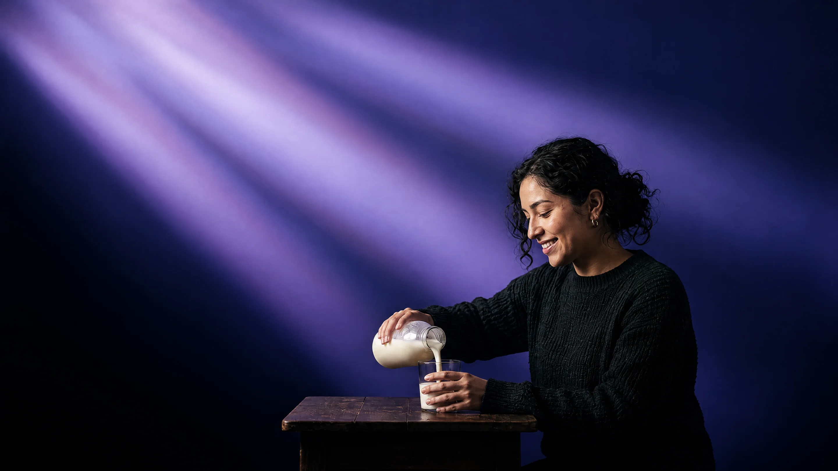 A woman pouring kefir into a glass in beams of violet light